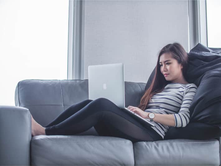 Una donna seduta sul divano utilizza un laptop